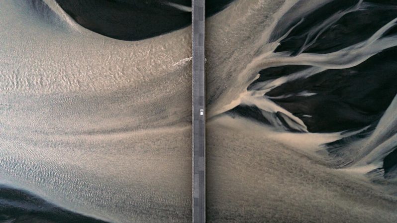 Car driving over a bridge crossing a braided river seen from directly above, Iceland
